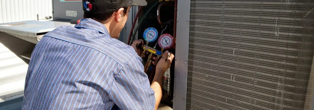 HVAC technician servicing a condenser unit in Webster