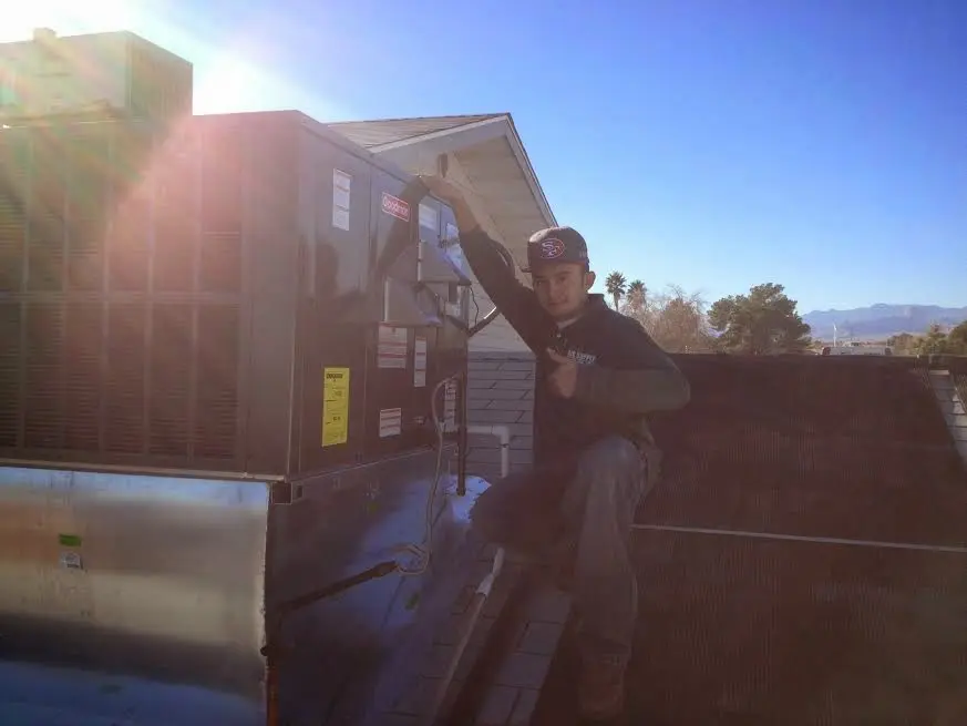 HVAC technician performing Heat Pump Repair on a rooftop unit in Webster